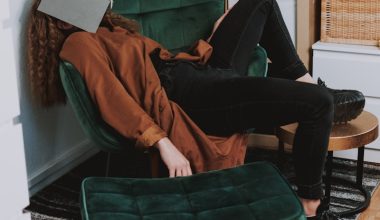 woman in red jacket and black pants sitting on green sofa chair