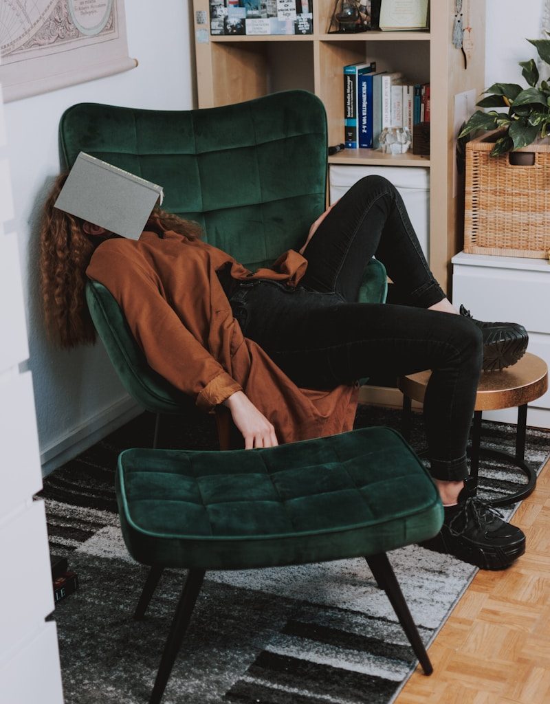 woman in red jacket and black pants sitting on green sofa chair