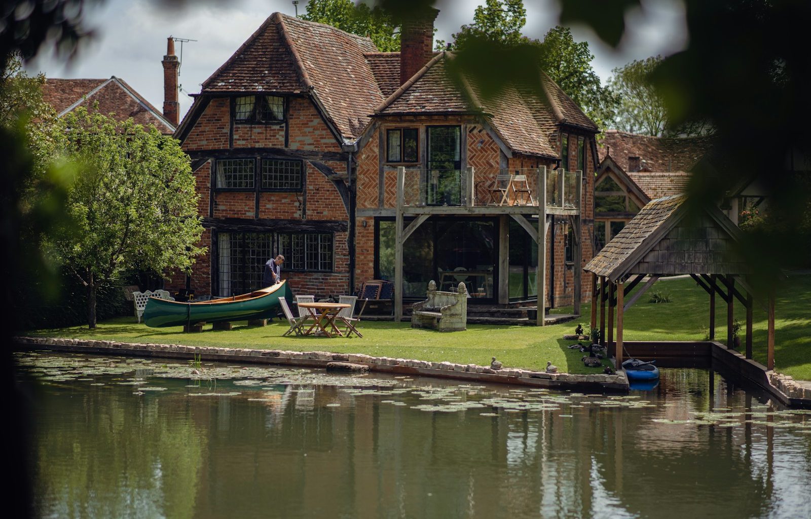 a house with a boat on the water in front of it